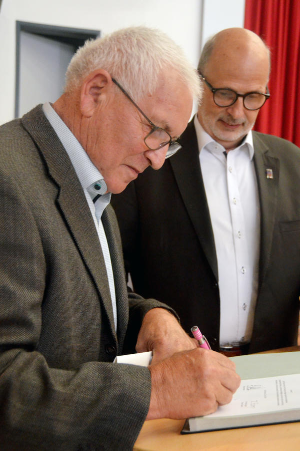 Stadtrat Jürgen Schulz unterschreibt die Urkunde zum abgelegten Diensteid. Im Hintergrund Bürgermeister Erhard Walther.