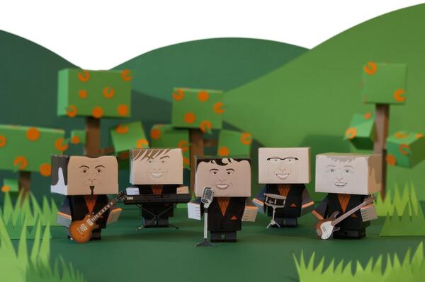 Abgebildet als Papp-Figuren stehen die f&uuml;nf Musiker der Gruppe Orange Box vor einer gr&uuml;nen Wiese.