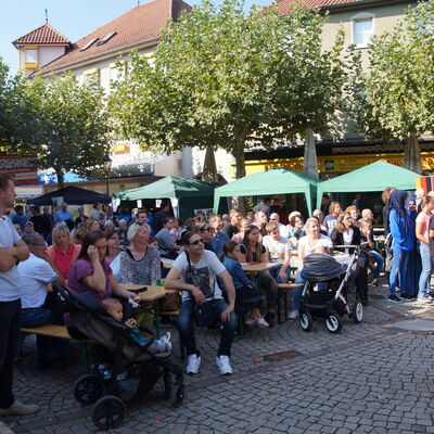 Gespannt sitzende Menschen zur Eröffnung der Interkulturellen Wochen 2018 auf dem Sandböhlplatz in Groß-Gerau.