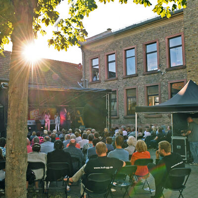 Blick vom Hof über das Publikum auf die Bühne im Rahmen des Sommerfestivals GG LOKAL in Dornheim, Groß-Gerau.