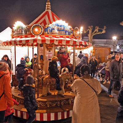 Kleines Kinderkarussell mit fahrenden Kindern unter Aufsicht der Eltern auf dem Weihnachtsmarkt in Groß-Gerau.