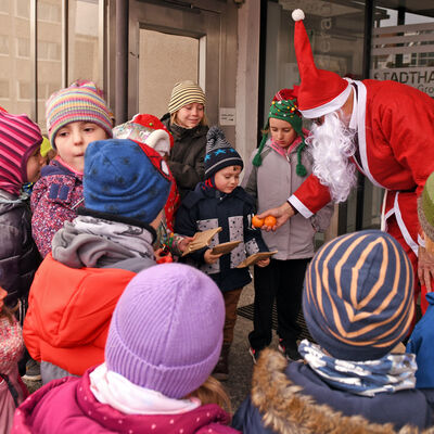 Halbkreis von Kindern, die ein Geschenk vom Nikolaus erhalten.