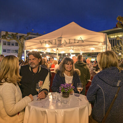 Unterhaltende Menschen an einem Stehtisch bei einem Glas Wein beim Frühlingserwachen in Groß-Gerau.