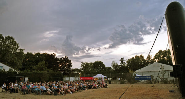 Sitzendes Publikum mit Blick auf die Leinwand beim Open-Air-Kino auf den Alten Tennisplätzen in Groß-Gerau.