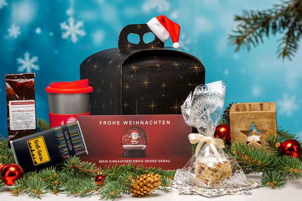 Groß-Gerauer Weihnachtsbox mit Tee, Schokolade, To-Go-Kaffeebecher, Stadtgutschein GG-Scheck, Stollenkonfekt und einem Windlicht aus Holz.