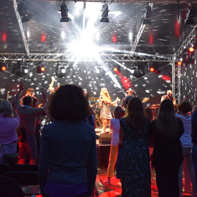 Blick auf die mit einer Discokugel angestrahlte Bühne mit der Band ABBA Explosion beim Kultursommer GG LOKAL in Groß-Gerau.