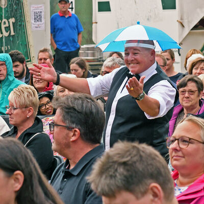 Comedian Woody Feldmann läuft durch das Publikum mit Schirmmütze auf dem Kopf.