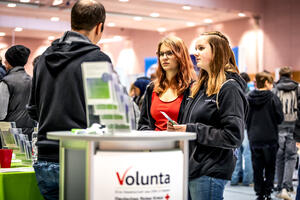 Zwei junge Frauen, die sich auf der Ausbildungsb&ouml;rse an einem Stand von Volunta beraten lassen.