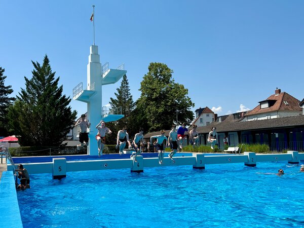 Eine Vielzahl an jungen Menschen springt von den Startbl&ouml;cken ins k&uuml;hle Nass des Gro&szlig;-Gerauer Freibads