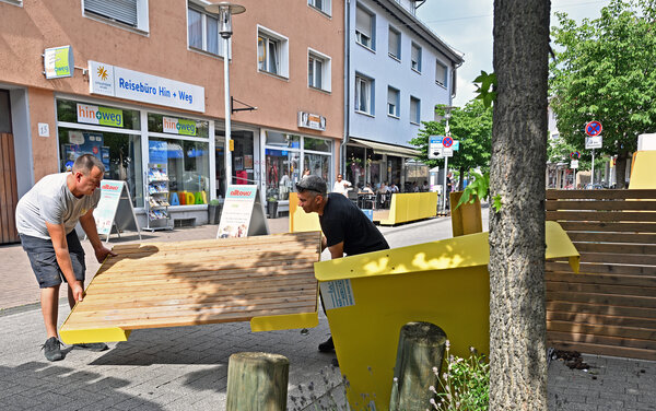 Zwei M&auml;nner bauen die Stadtm&ouml;bel in der Innenstadt Gro&szlig;-Geraus ab und transportieren eine Bodenplatte.