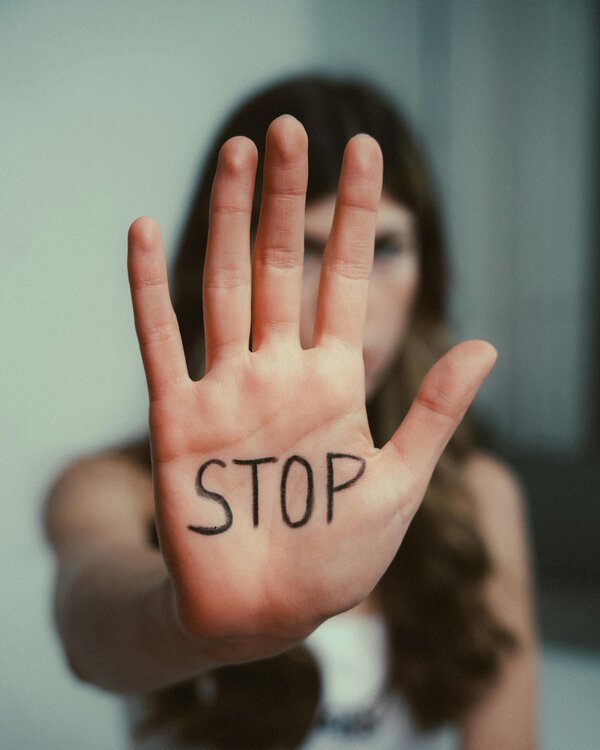 Eine ausgestreckte Hand mit gespreizten Fingern, auf der "Stop" steht.