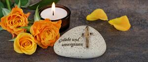 Grabschmuck: Kerze, Gedenkstein, Blumen.